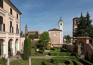 Historisches Anwesen des Sunstar Hotels Piemont mit gepflegtem Garten und Kirchtürmen im Hintergrund