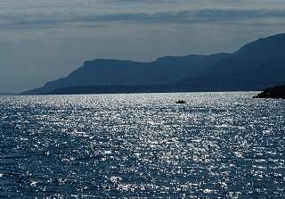 Lumière du soleil scintillant sur la mer Méditerranée devant la silhouette des montagnes côtières de Ligurie