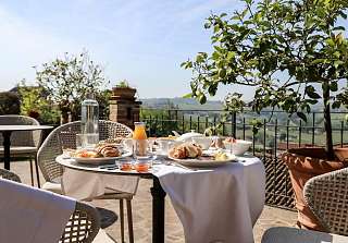 Gedeckter Frühstückstisch auf der Sonnenterrasse des Sunstar Hotels Piemont mit Blick über die hügelige Landschaft des Piemonts, Croissants, Orangensaft und frischen Zutaten